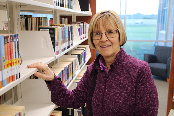 Woman with hand resting on a bookshelf